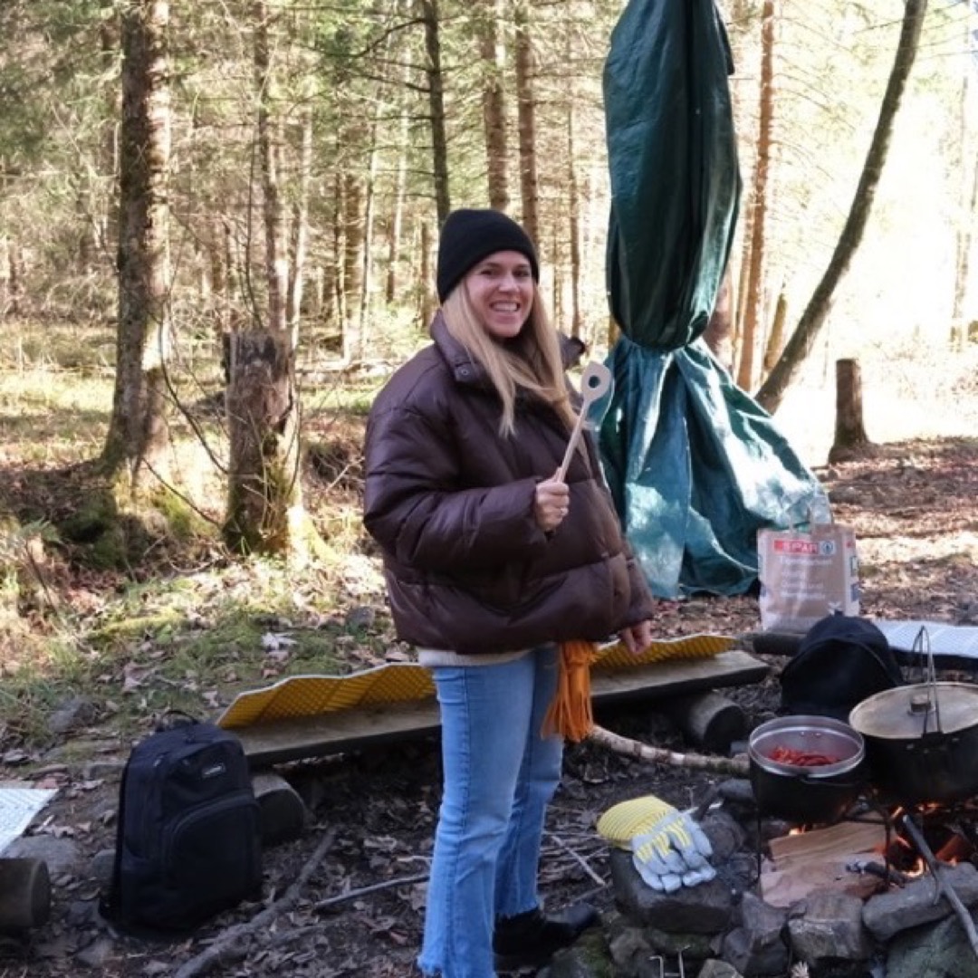 Teilnehmerin kocht über dem Feuer an einem Teamtag im Wald