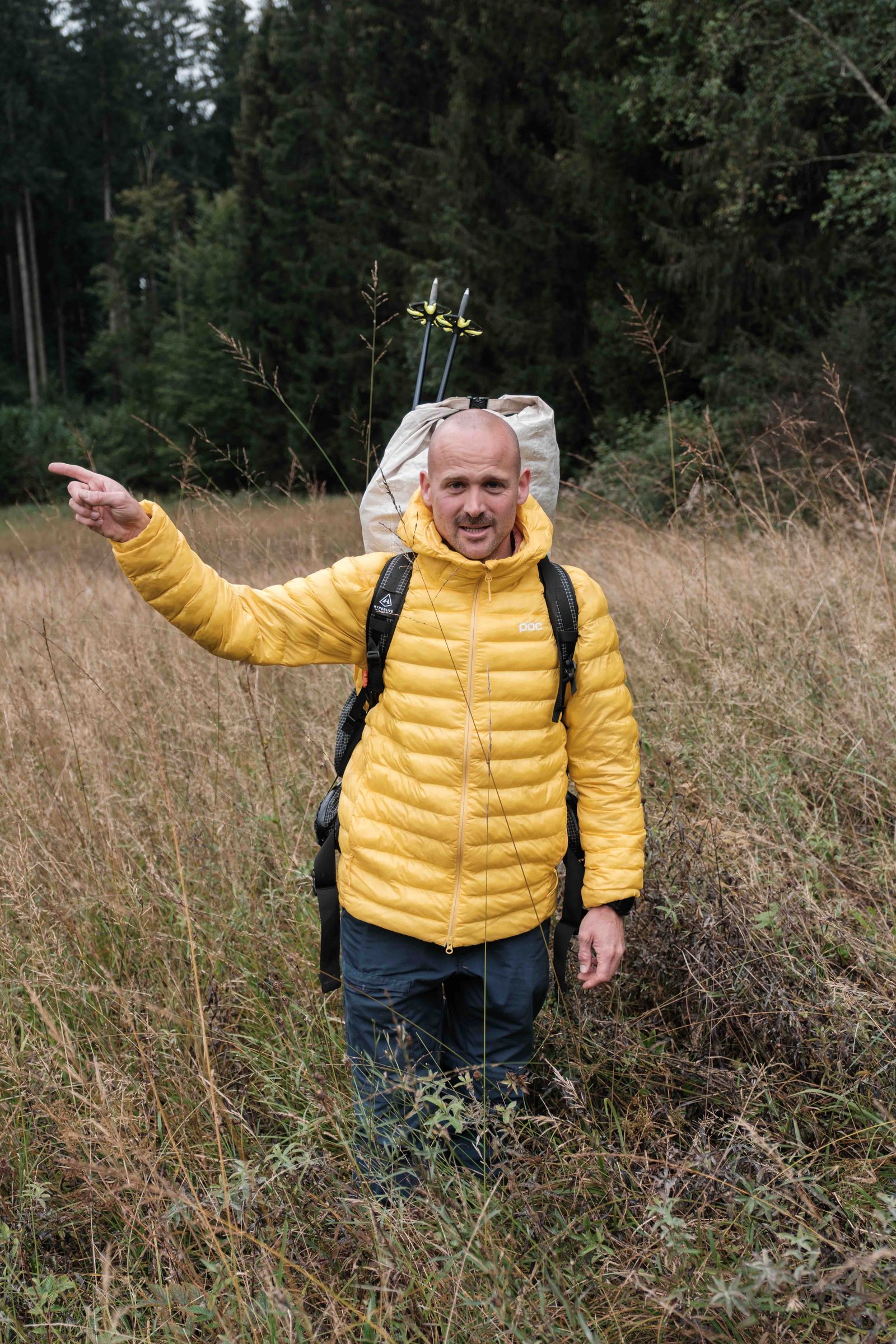Outdoor Guide Manuel Seiler mit Rucksack zeigt den Weg über eine Wiese