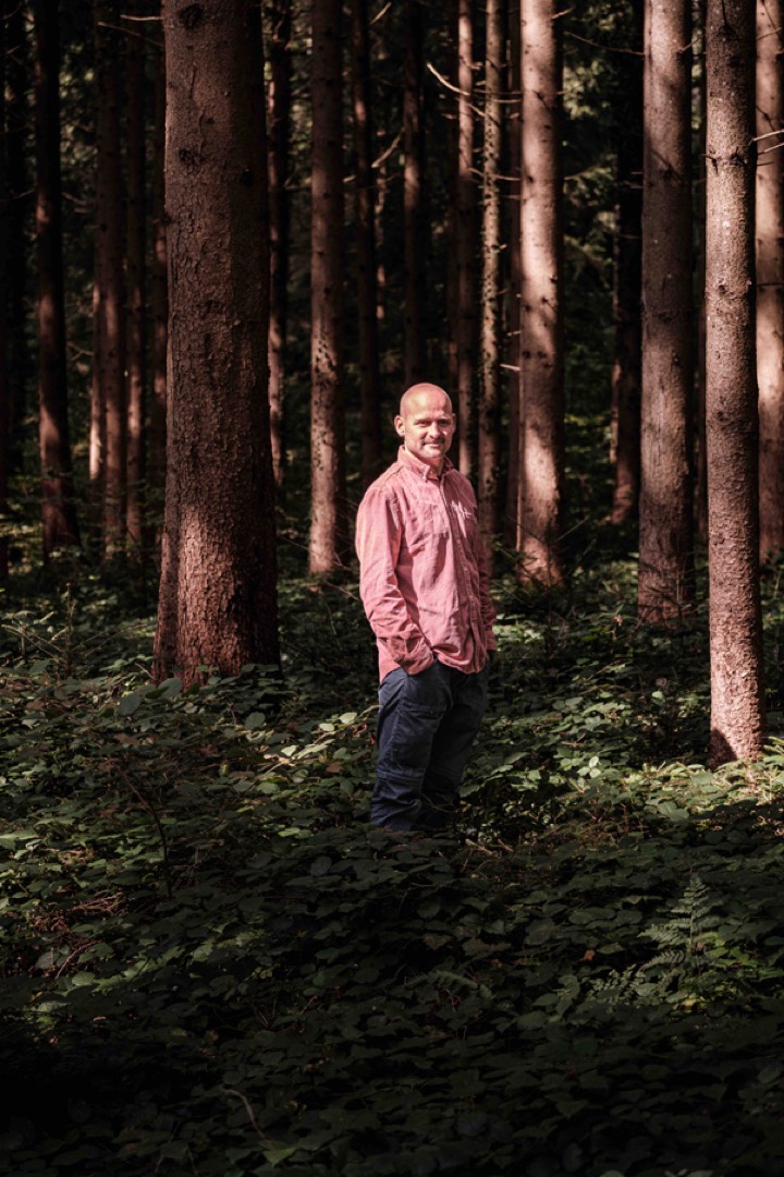 Erlebnispädagoge Manuel Seiler mitten im Wald mit schöner Lichtstimmung zwischen den Bäumen