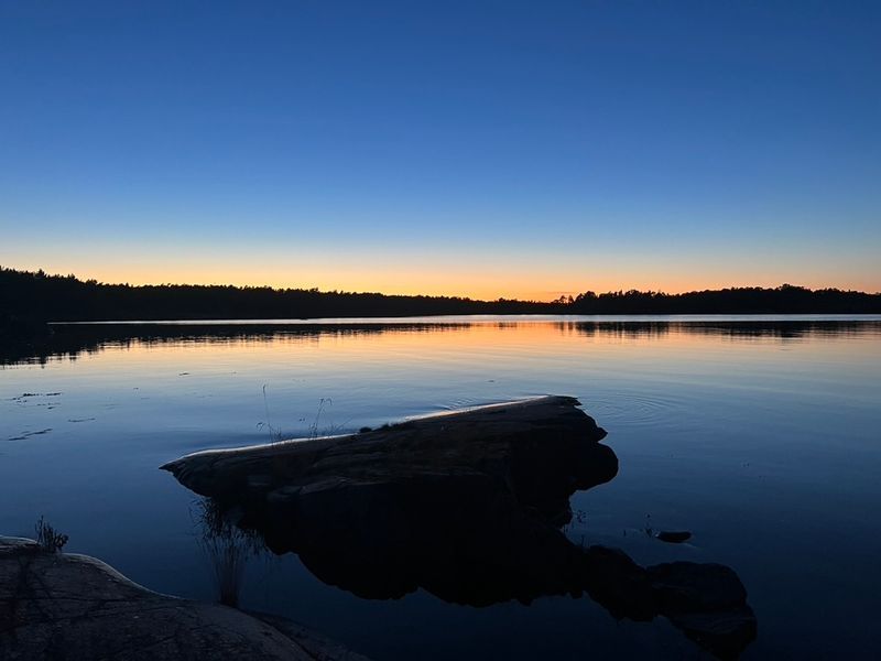 Stiller See mit Felsen im Abendlicht